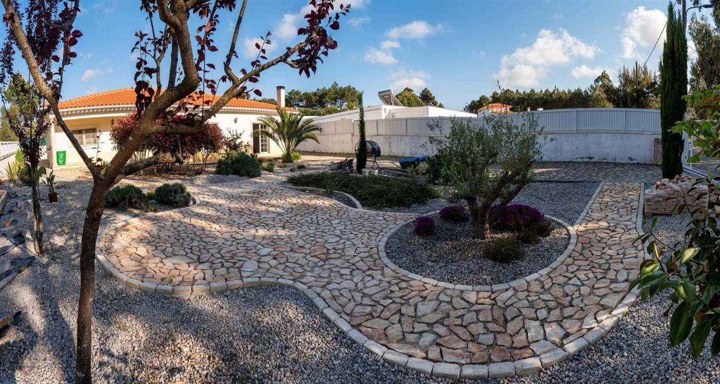 A panoramic view of finished natural-stone crazy-paving paths winding around a Silver Coast villa with palm trees and stone planters